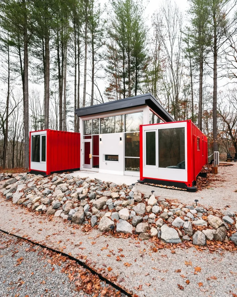 Shipping container home with bright red and white sections and a rock garden.