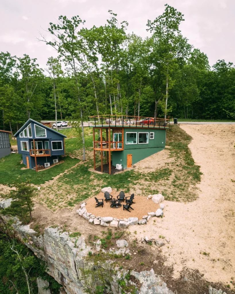 Green shipping container home perched on a cliff edge with a fire pit area. - Real shipping container homes