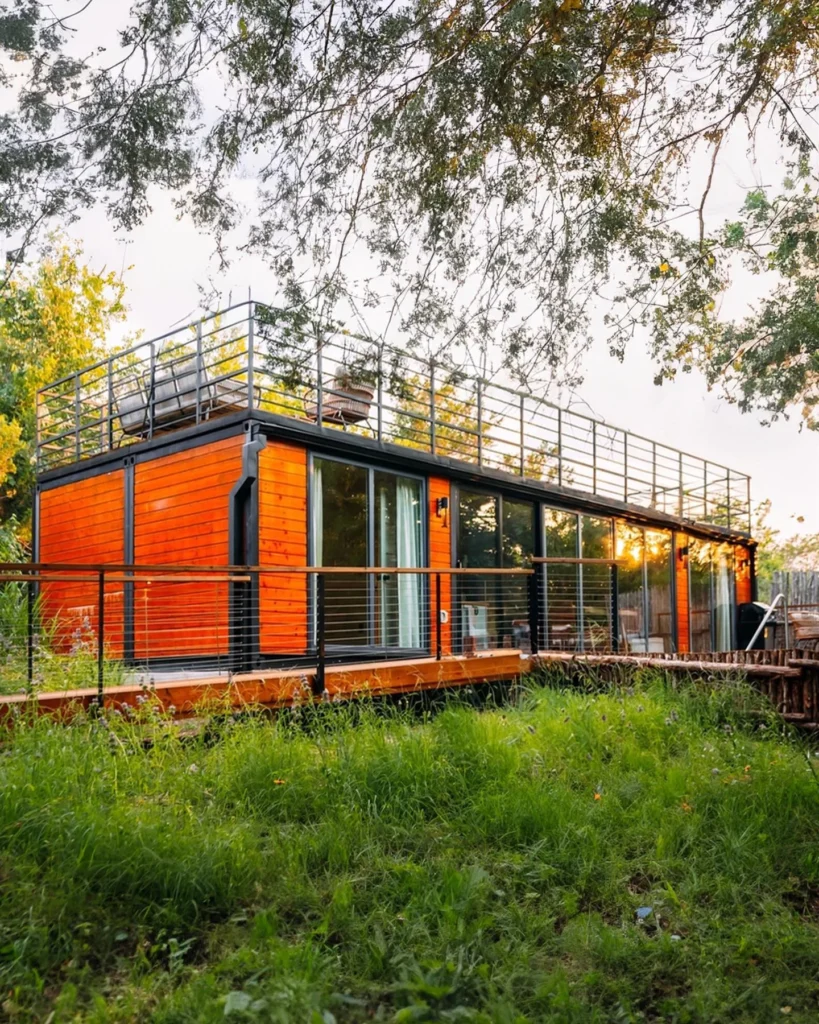 Shipping container home with large rooftop deck and wooden siding accents.