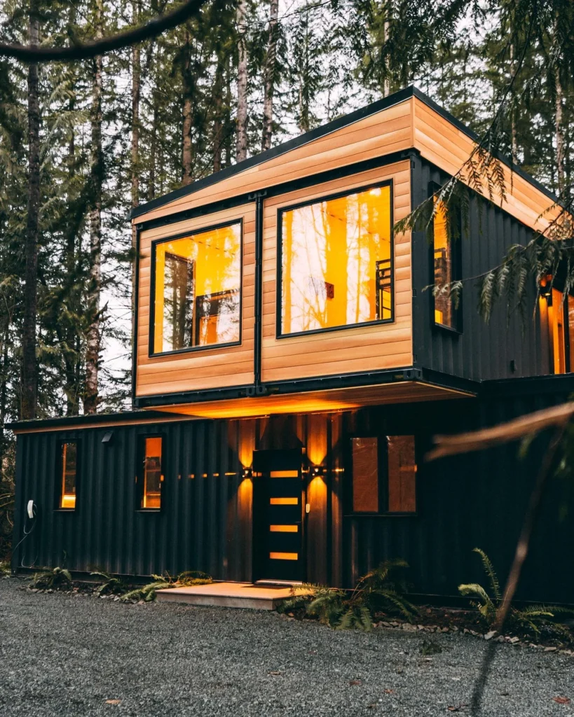 Two-story shipping container home with wood cladding and modern design.