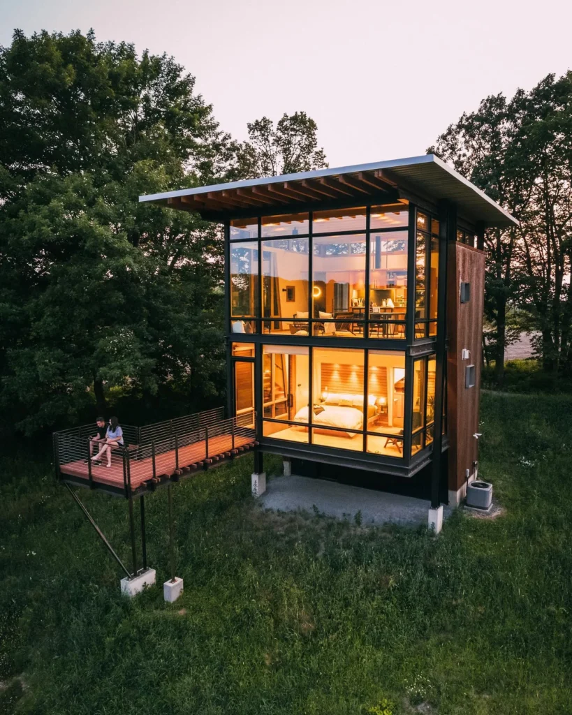 Stunning house design with glass walls and elevated walkway.