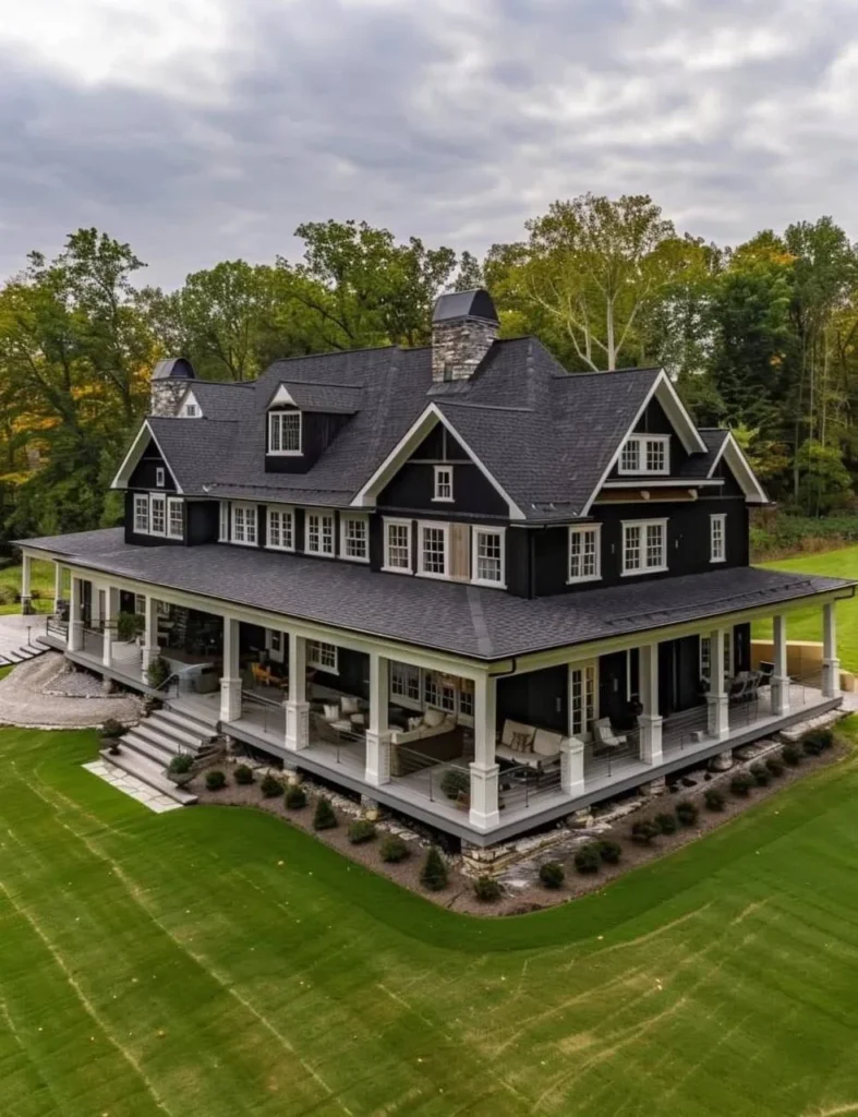 Two-story modern farmhouse with dark siding, white trim, wrap-around porch, dormer windows.