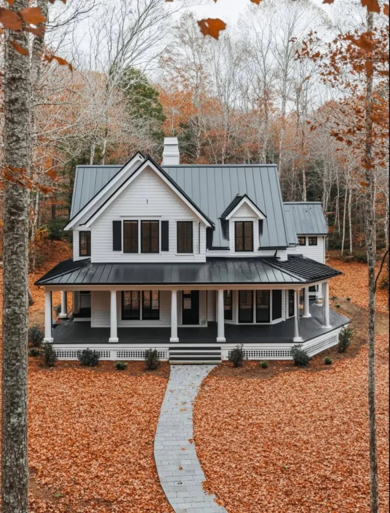 White modern farmhouse with black trim, wrap-around porch, metal roof, surrounded by trees.