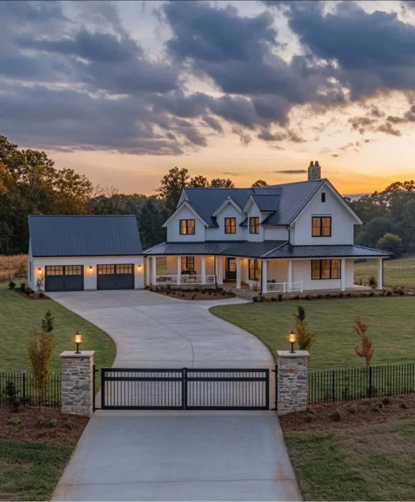 Modern farmhouse with detached garage, black and white exterior, wrap-around porch, gated entrance.