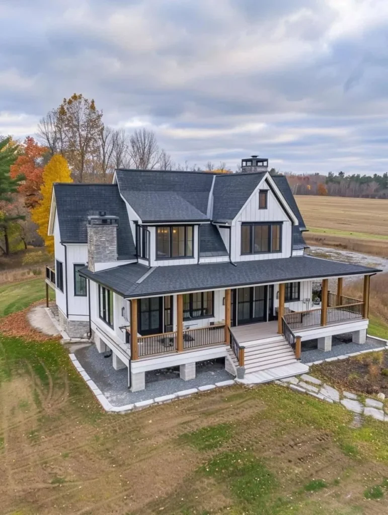 Two-story modern farmhouse with wrap-around porch, stone chimney, black trim.