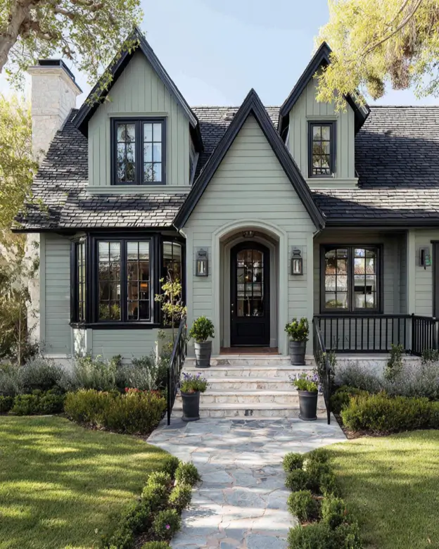 A charming and symmetrical sage green house with black trim, showcasing perfectly balanced twin gables for a storybook look.
