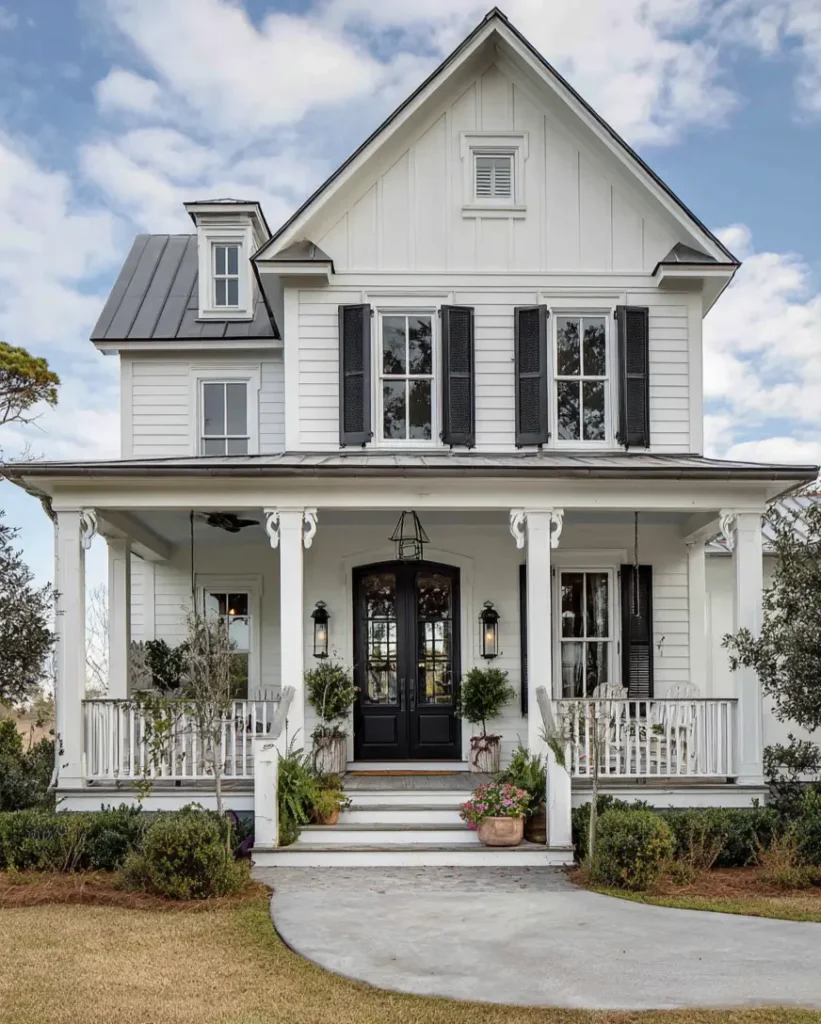 A charming white and black farmhouse exterior with black double doors and decorative porch railings.