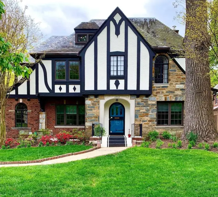 A modern Tudor-style house exterior with high-contrast black and white timbering and a vibrant blue front door.