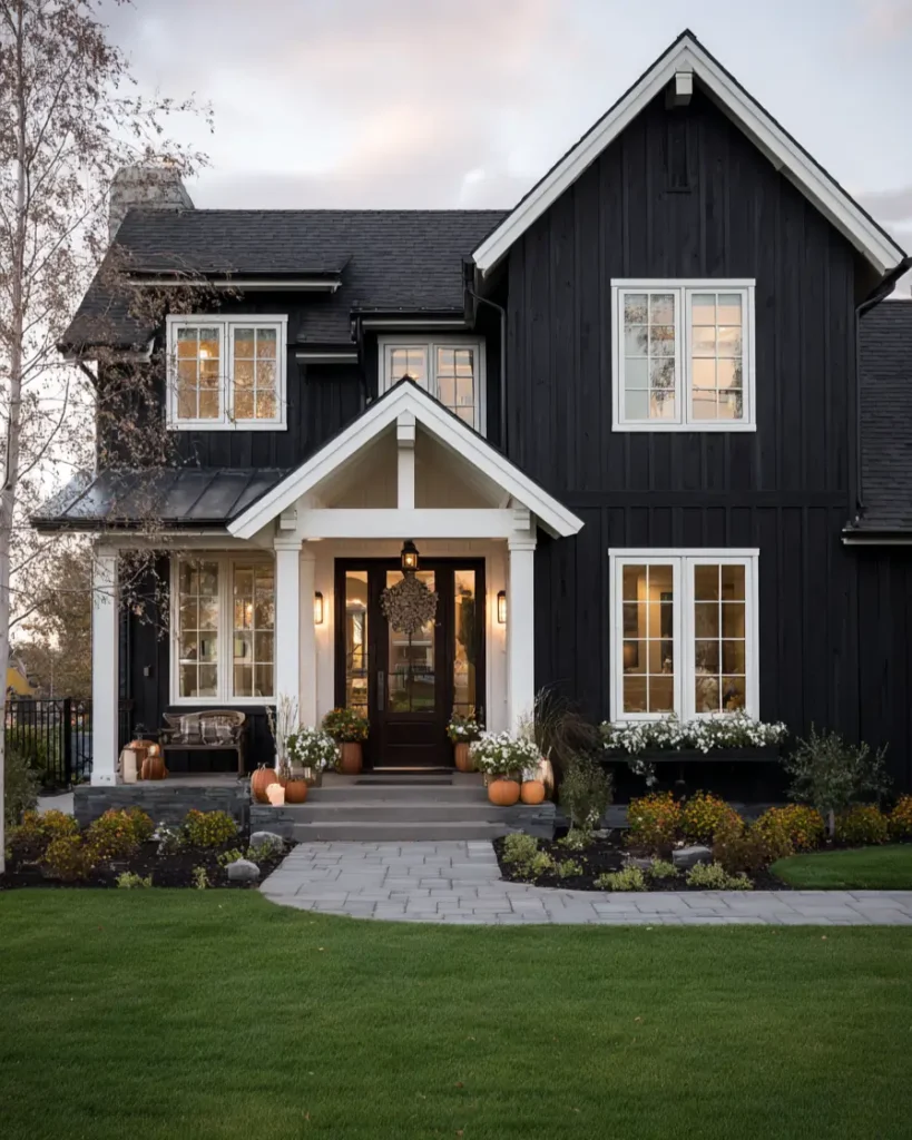 The exterior of a dark farmhouse with a bright white gabled portico creating a welcoming entry.