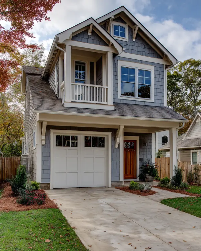 Two-story modern craftsman style house on a narrow lot, featuring blue-gray shingle siding and a charming second-story balcony.