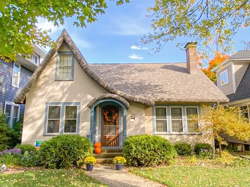 Charming Tudor-style house exterior featuring a whimsical, curved roofline and soft blue window trim.