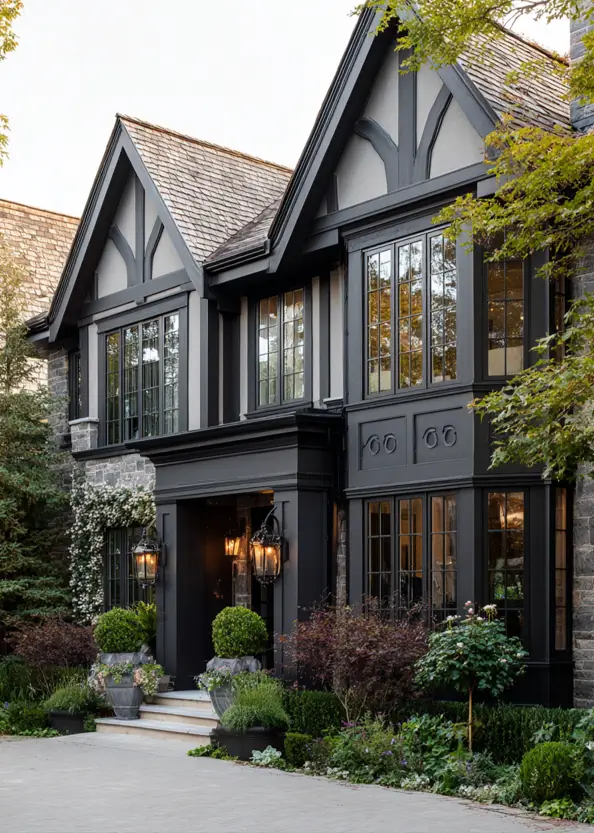 A moody modern Tudor house exterior with dark charcoal trim, grey stone, and a grand black entryway portico.
