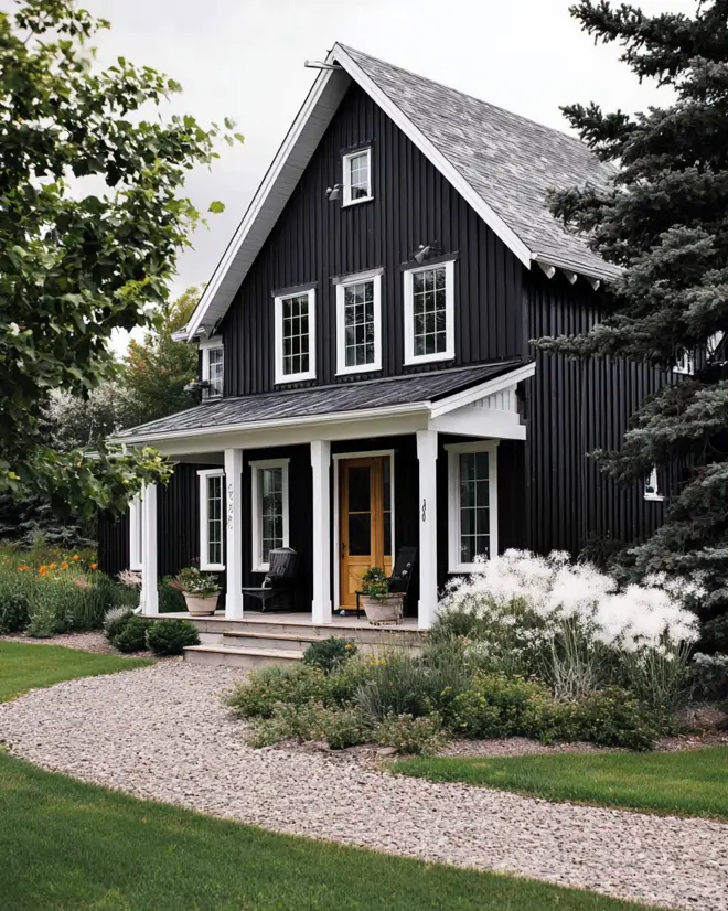 A simple and classic black farmhouse with a clean white porch and a natural wood door.
