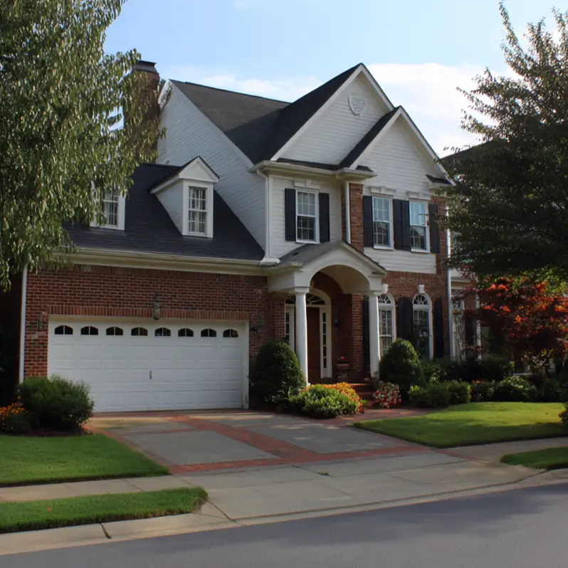 A classic suburban house exterior that combines a timeless red brick first floor with a lighter, white-sided second story for a stately and balanced appearance.