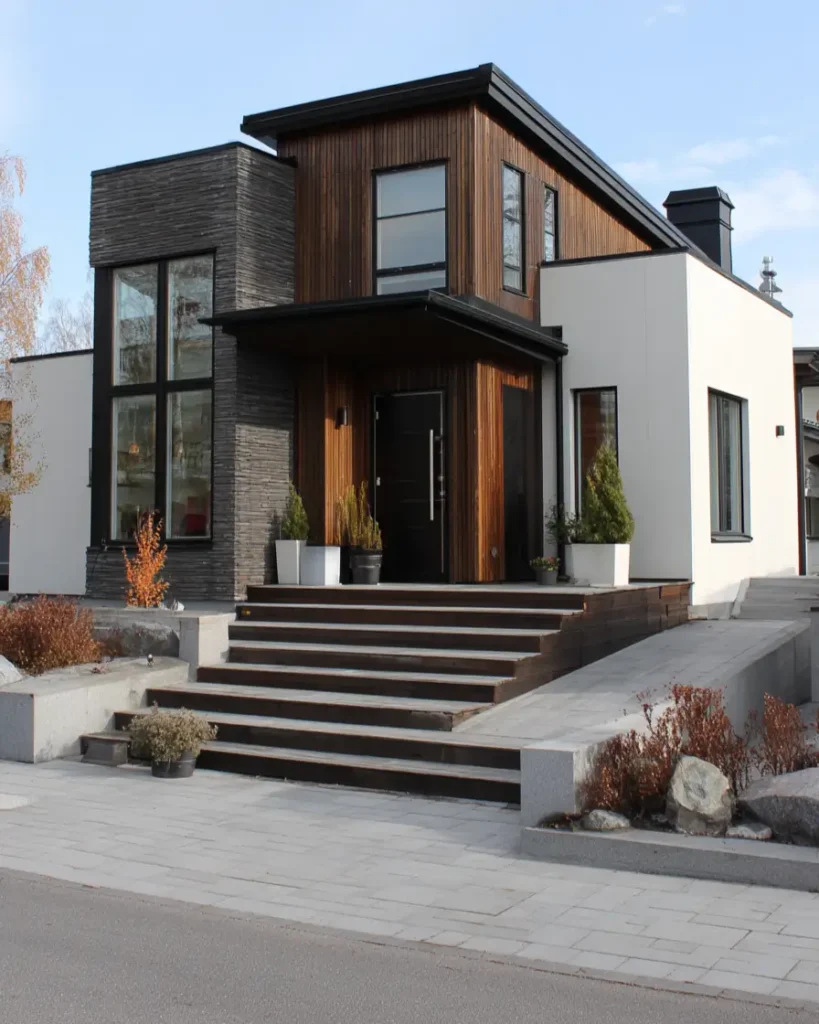 A modern Scandinavian exterior with stacked stone, wood siding, and white panels, featuring a wide entrance staircase.