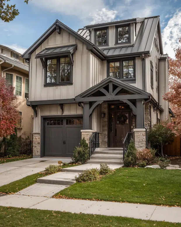 Contemporary craftsman house with light vertical siding, dark trim, a standing-seam metal roof, and a prominent gabled entryway.
