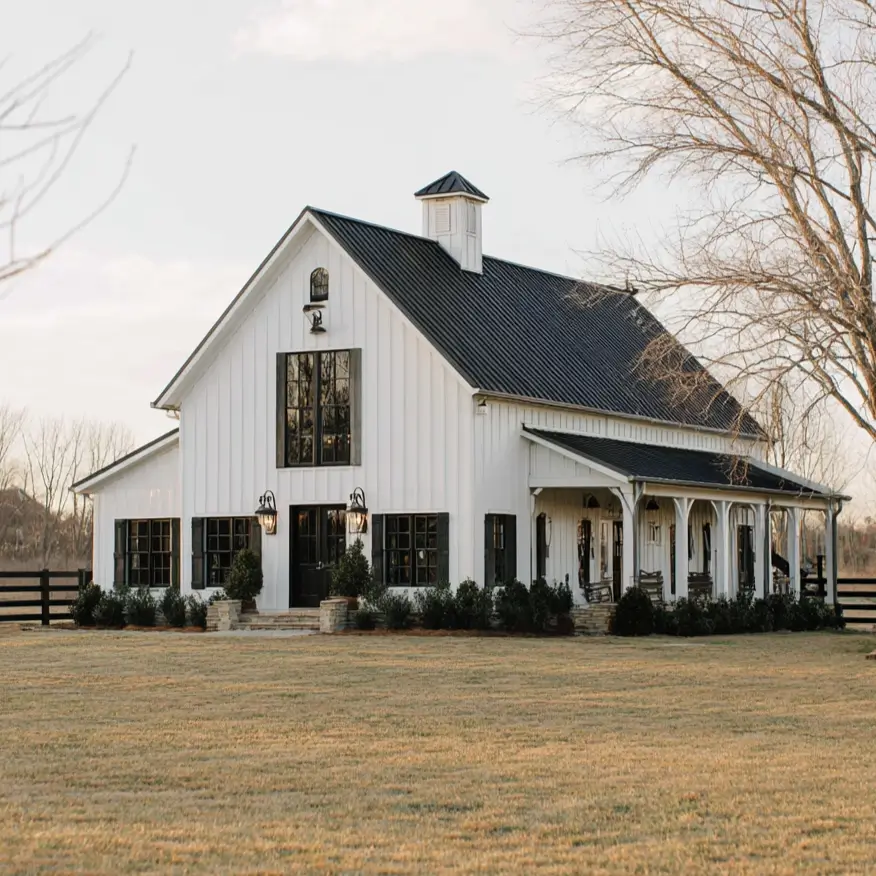 A grand white farmhouse with a modern barn-style design, a prominent cupola, and a large arched window.