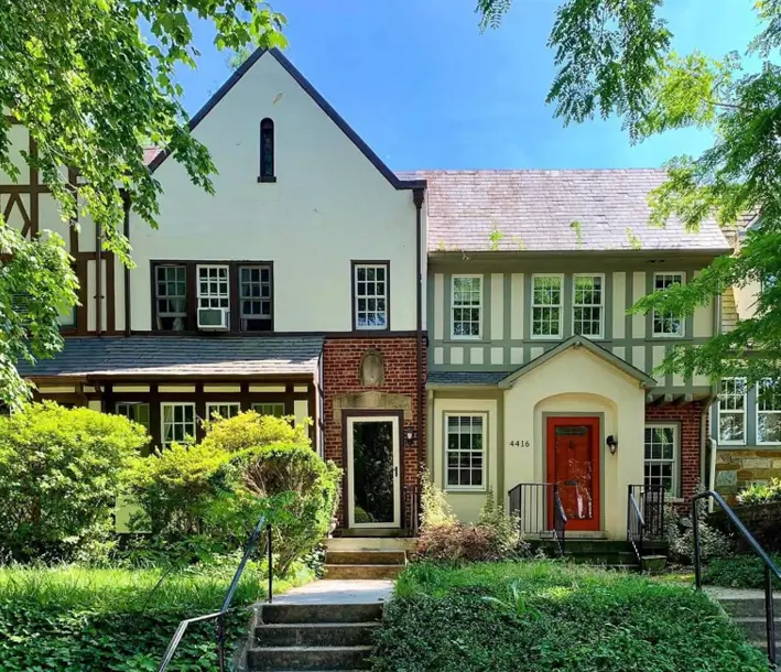 Tudor-style house exterior with a mix of rich materials including a brick base, stucco, and half-timbering.