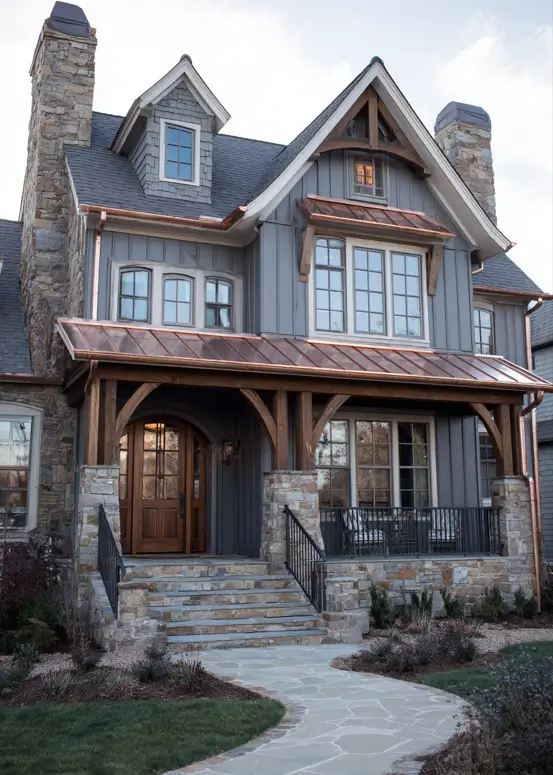Luxury modern craftsman house featuring gray vertical siding, a distinctive copper porch roof, and large stone chimneys on either side.