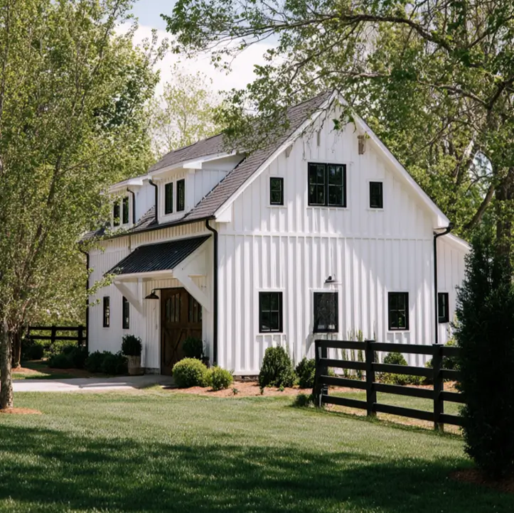 A crisp white modern barn-style home with a black fence defining the property.