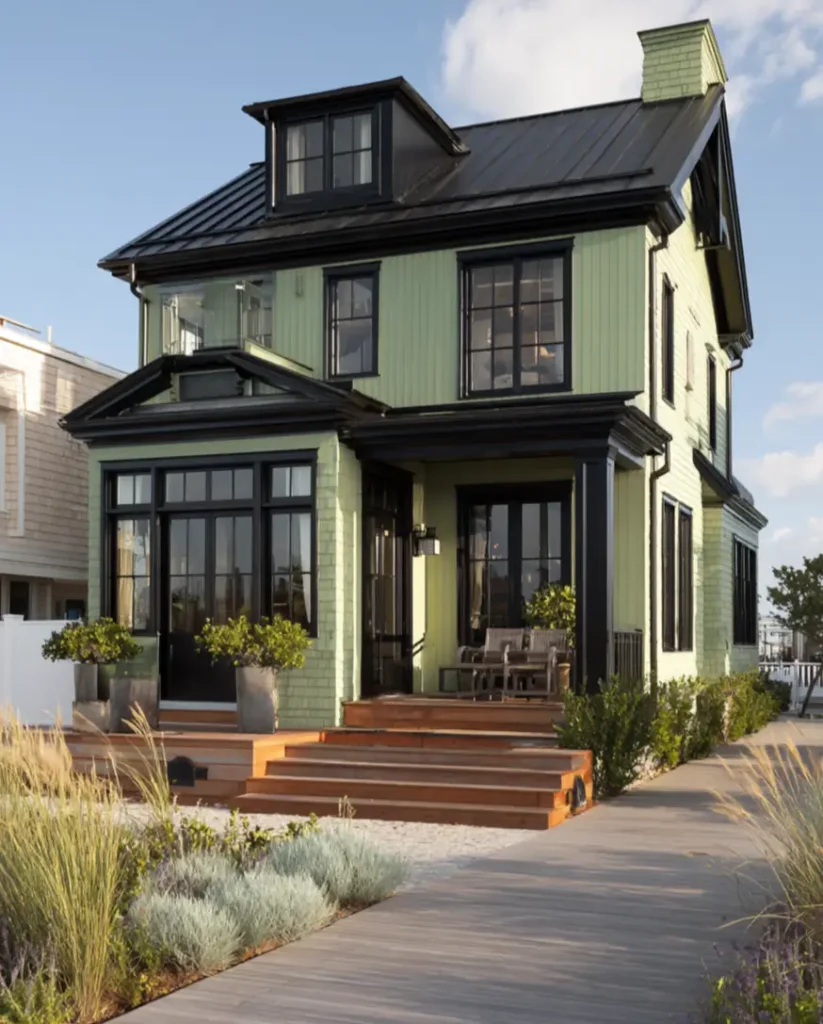A modern sage green beach house where extensive, generous black trim on the porch and windows makes a dramatic statement.