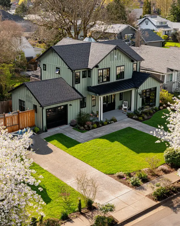 The quintessential modern sage green farmhouse exterior, showing board-and-batten siding and a relaxing covered front porch.