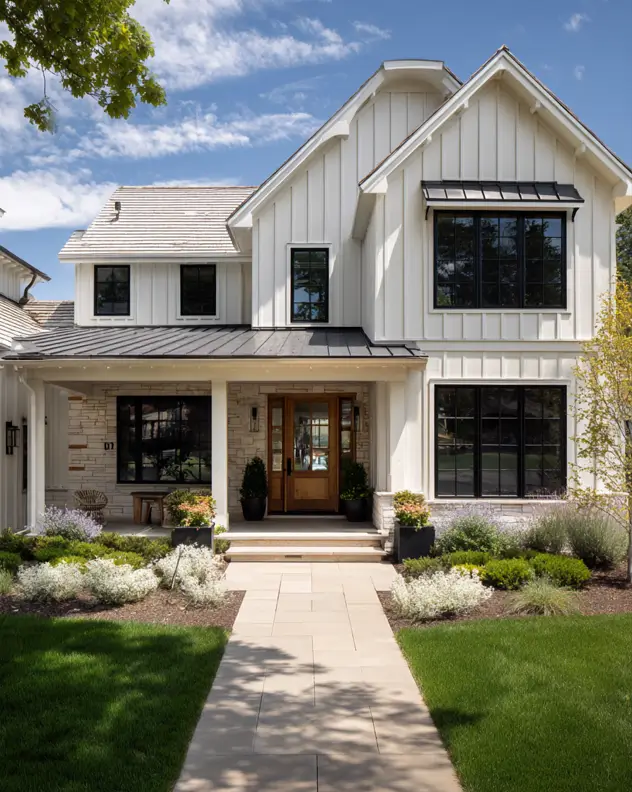 The beautiful facade of a modern suburban farmhouse featuring crisp white board-and-batten siding, bold black-framed windows, and a warm wood front door.