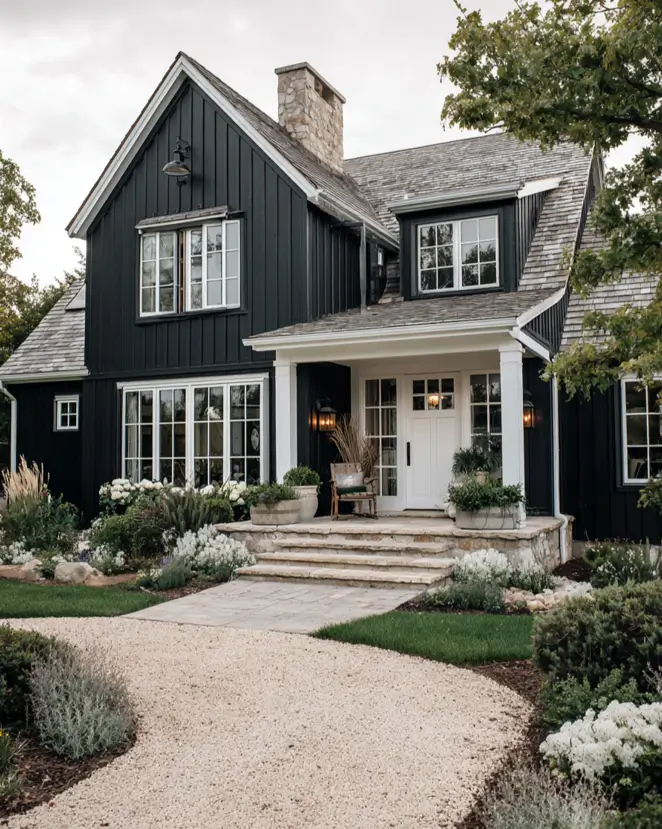 A black and white farmhouse exterior with a prominent stone chimney and a rustic natural wood shake roof.