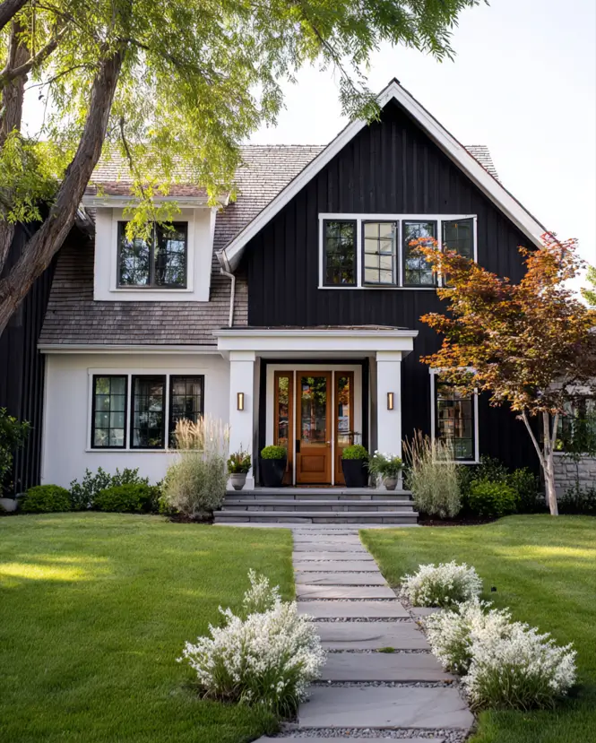 A modern farmhouse exterior with mixed materials, including a black gable and a lighter lower level.