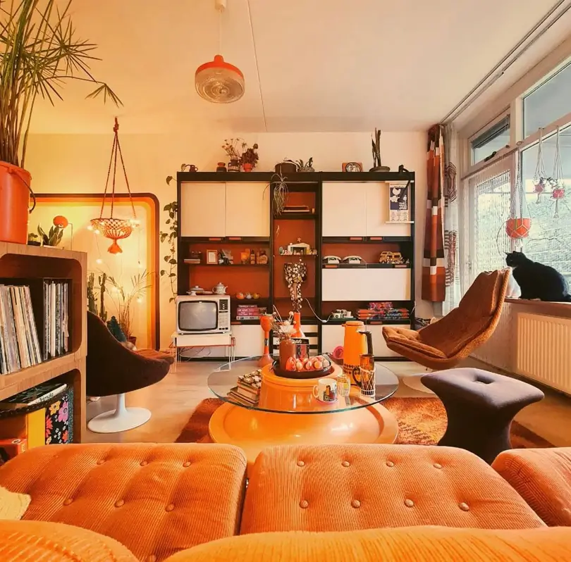 A 70s retro living room with an orange corduroy sofa, brown lounge chairs, and modular shelving.