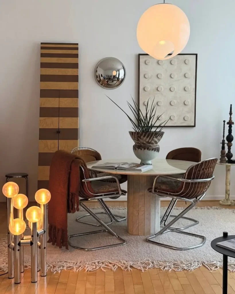 A chic small apartment dining nook with a round table, chrome chairs, and statement lighting creating a cozy interior design.