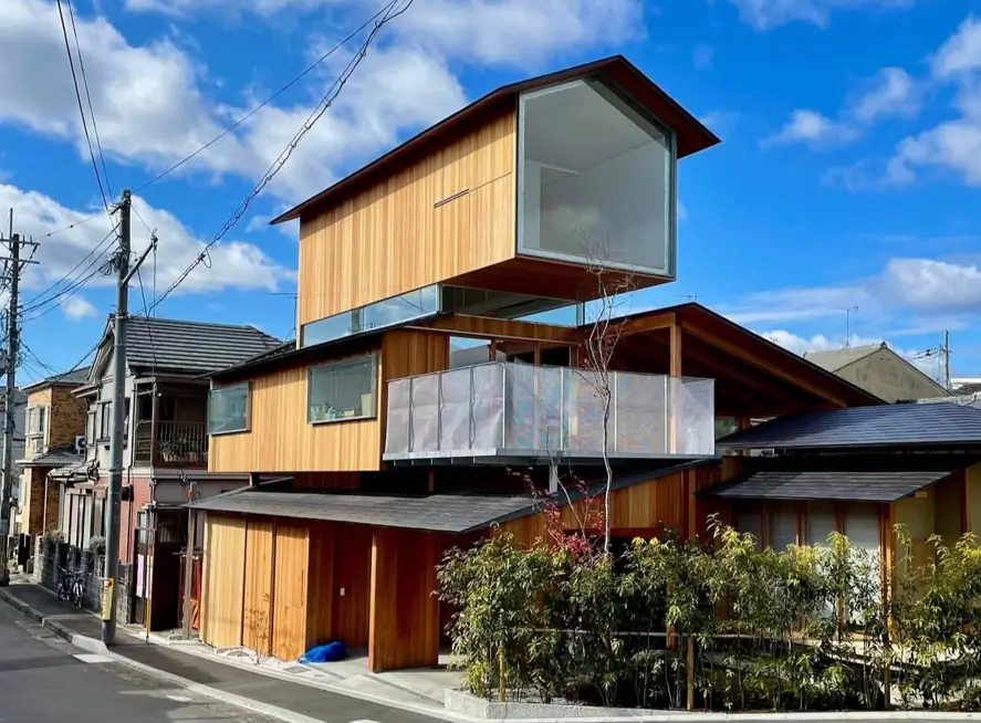 A modern Japanese house exterior with stacked wood levels and large windows.