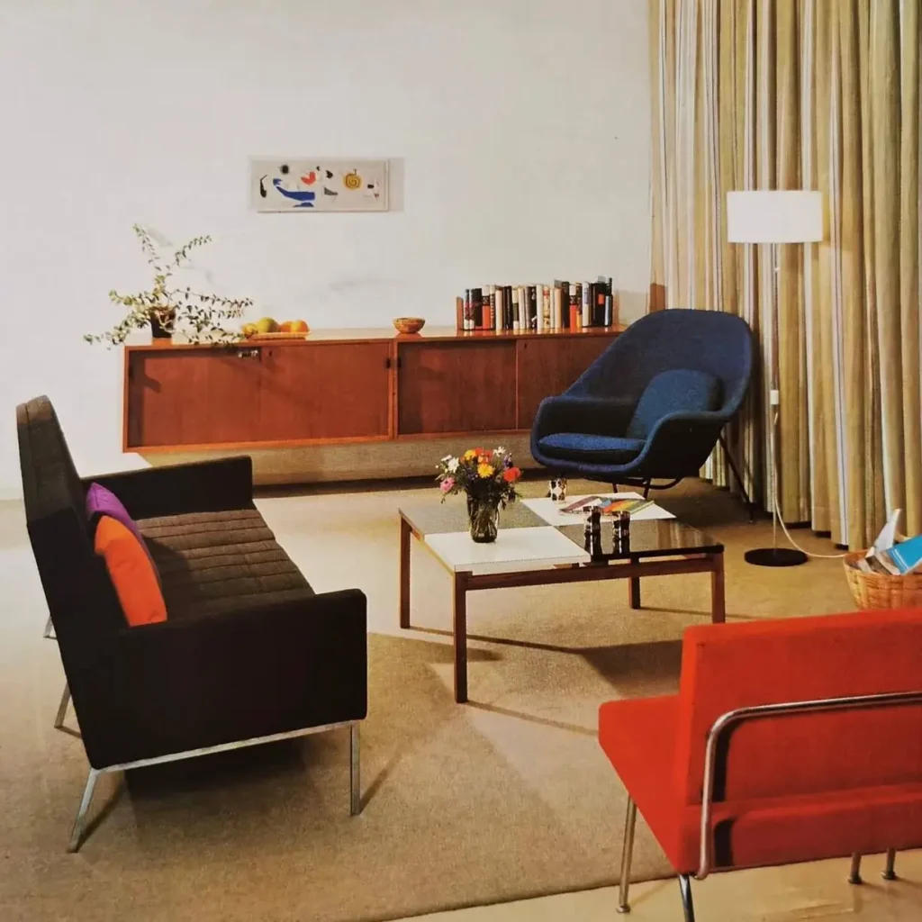 A 70s living room with a teak credenza, a blue sculptural chair, and chrome-legged seating.