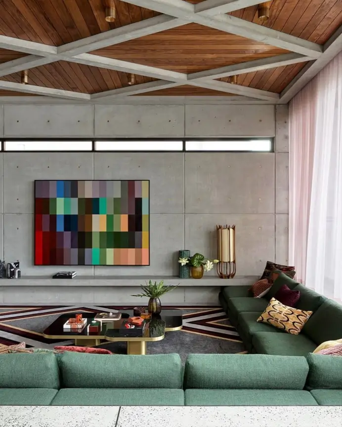 A modern living room showing 70s interior design styles with an olive green sectional, geometric rug, and wood coffered ceiling.