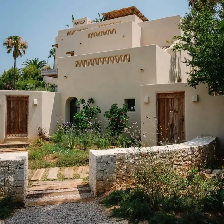 A rustic Mediterranean home with natural stone walls, wooden doors, and a gravel garden path.
