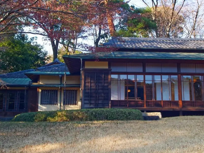 A classic Japanese style house exterior with a long wood veranda and sliding screens in a garden.