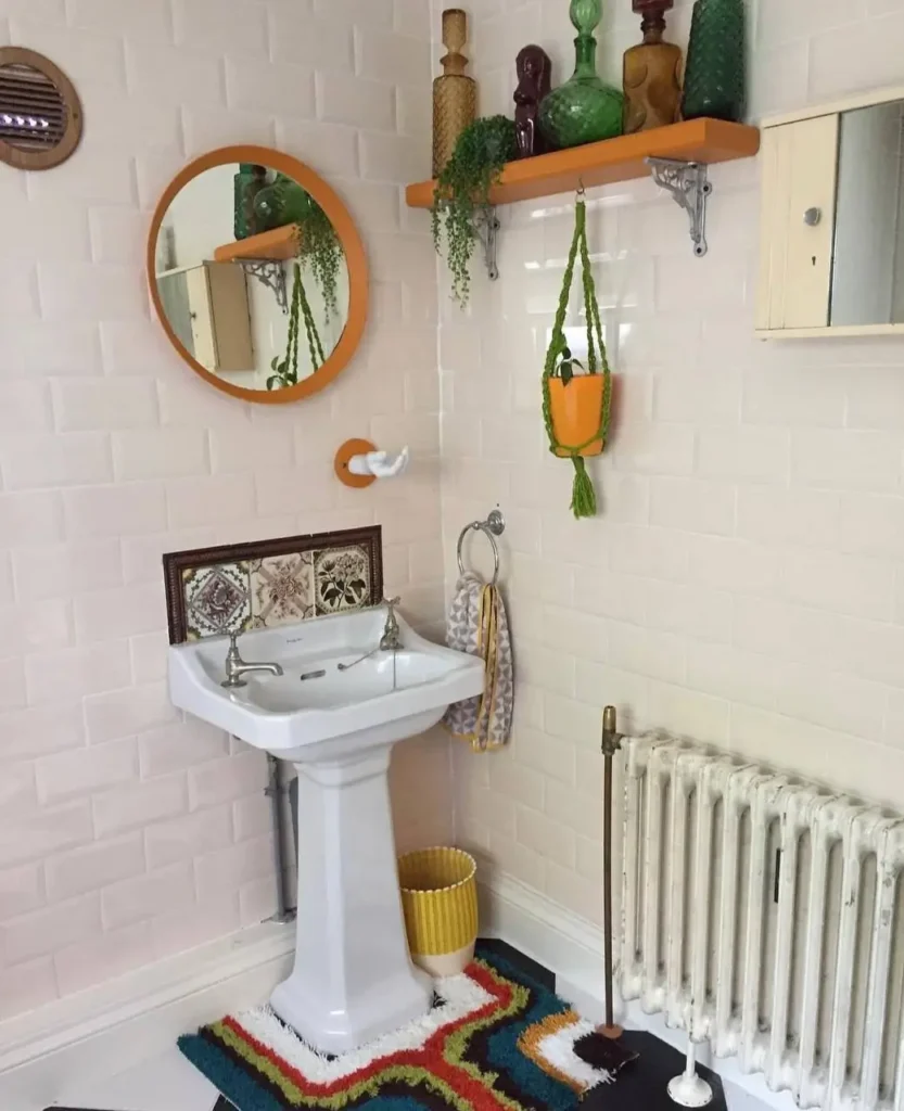 70s bathroom decor ideas shown in a neutral bathroom, including a colorful geometric rug and a round orange mirror.
