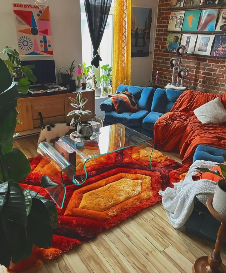 A 70s living room centered around a geometric shag rug, with an exposed brick wall and blue sofa.