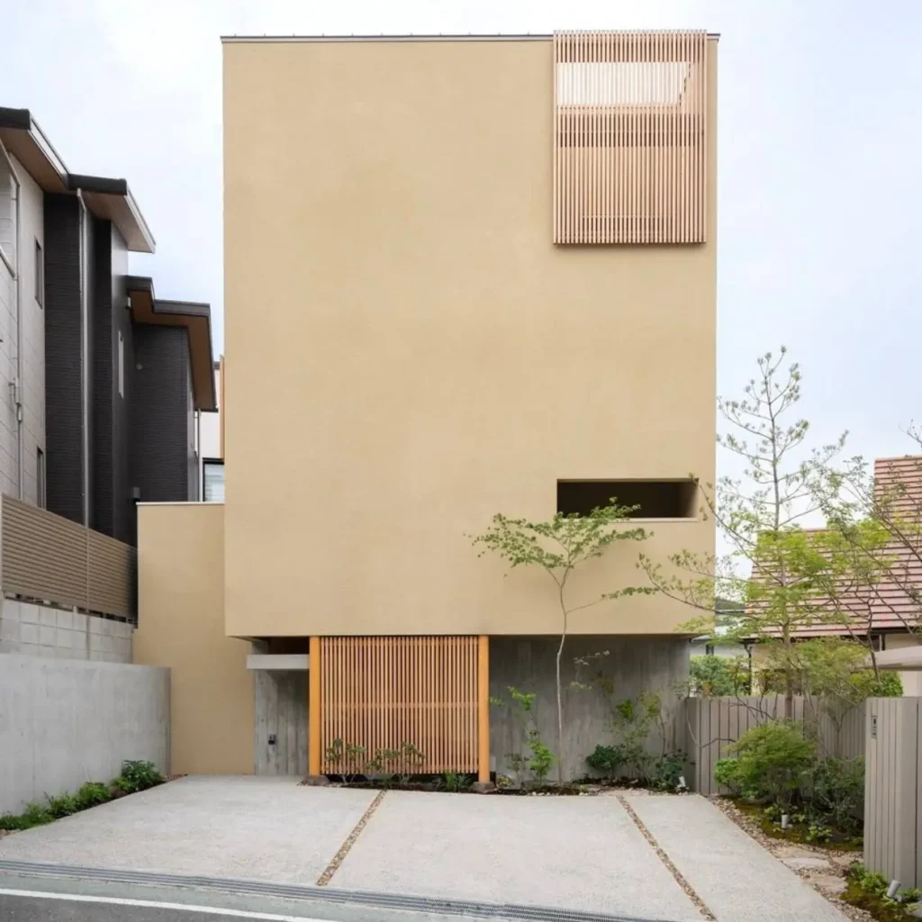 A modern Japanese house exterior by fujiwaramuroarchitects, featuring a minimalist beige stucco facade and wood slat details.