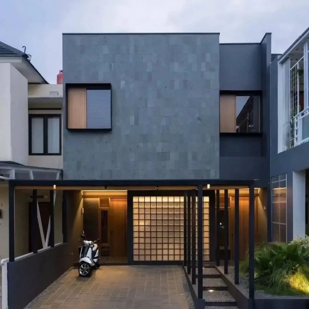 The Imah mulih house by Birka Loci, featuring a modern minimalist facade of textured gray stone and a glass block wall.