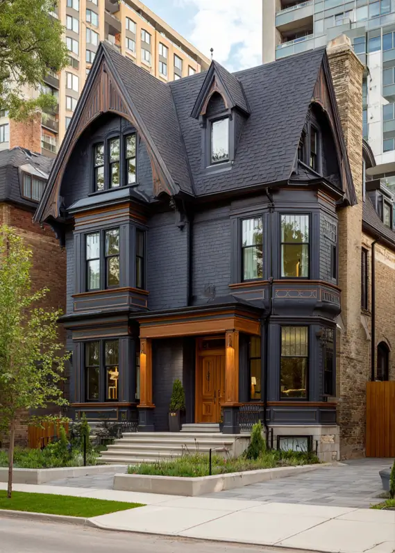 A dark gray modern Victorian house featuring warm wood accents on the porch and front door.