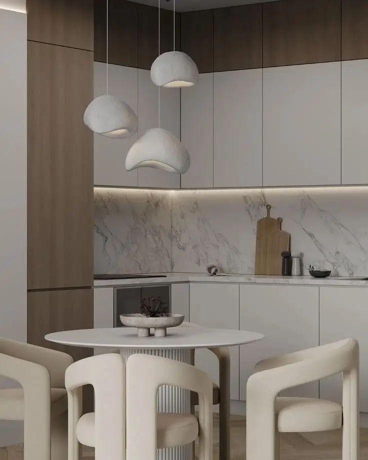 A small condo dining room idea with a round table and sculptural beige chairs under a cluster of organic pendant lights.