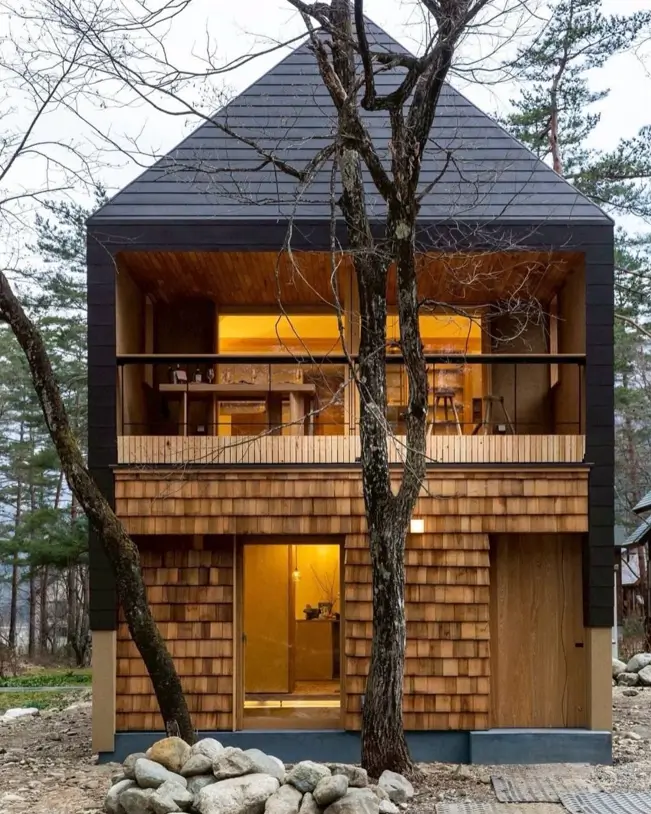 A modern Japanese style house with wood shingles and a black recessed balcony.