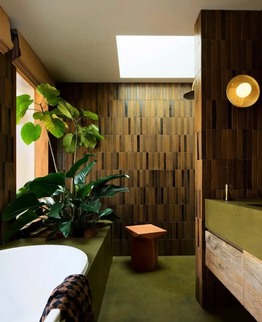 A bathroom with 70s interior decor, featuring brown vertical wall tiles, an olive green floor, and a rustic wood vanity.