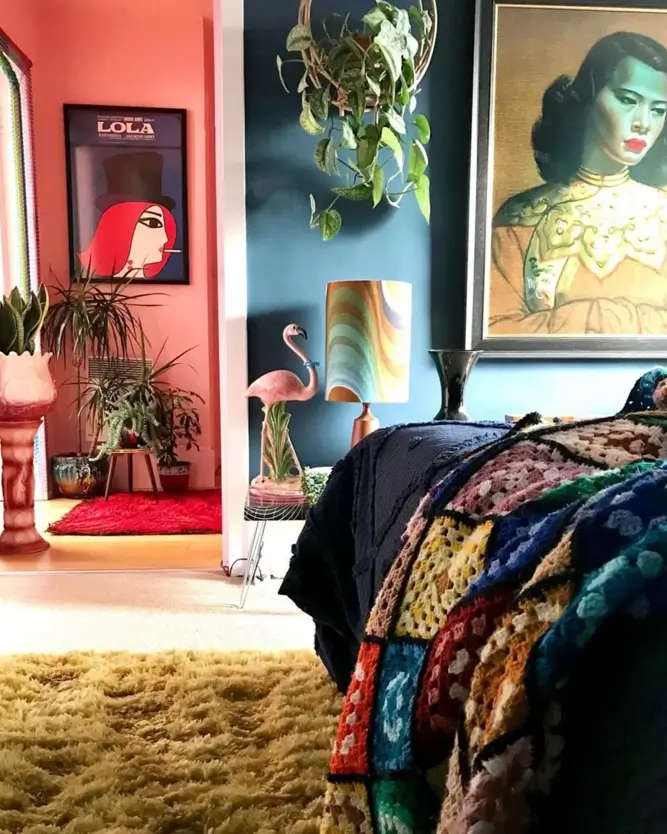 An eclectic 70s bedroom with a colorful crochet blanket, yellow shag rug, and blue walls.