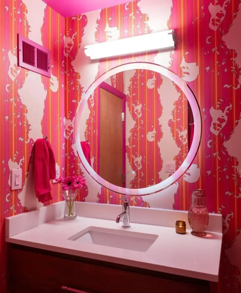A modern 70s bathroom with bold pink and orange psychedelic pop art wallpaper and a contemporary vanity.