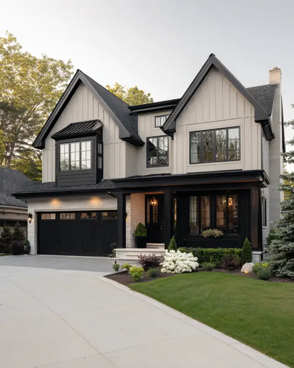 A modern beige house with a stone garage, vertical siding, and prominent black trim.