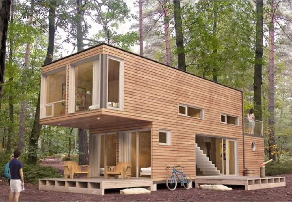 Modern minimalist woodland house with wood siding and a cantilevered second story surrounded by trees.