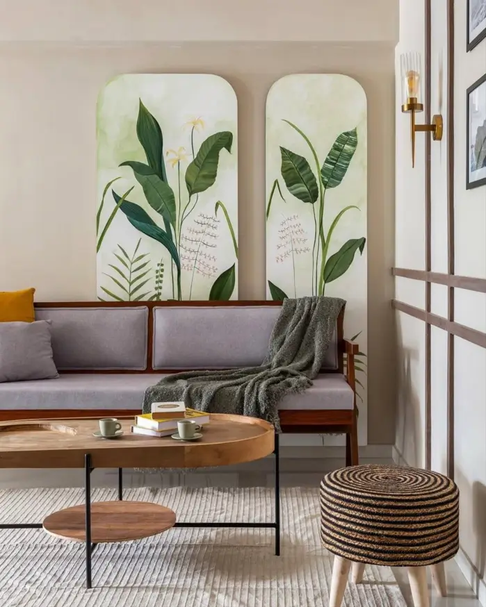 A neutral living room featuring a gray sofa, large botanical art panels, and a tiered wooden coffee table.