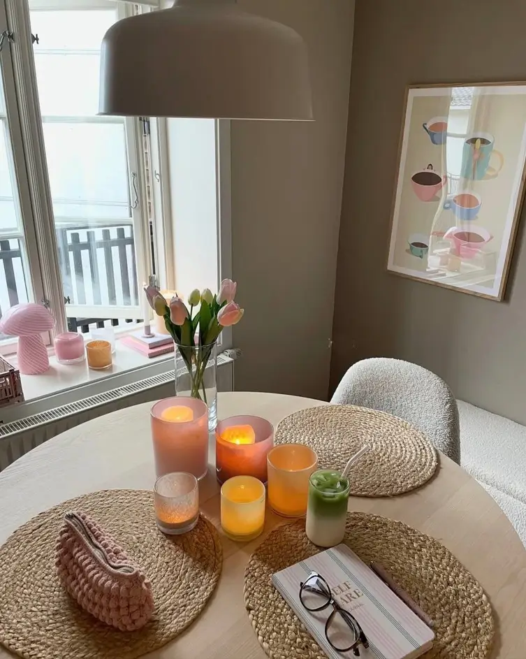 A cozy dining table in a small apartment with lit candles, fresh flowers, and woven placemats creating a warm ambiance.